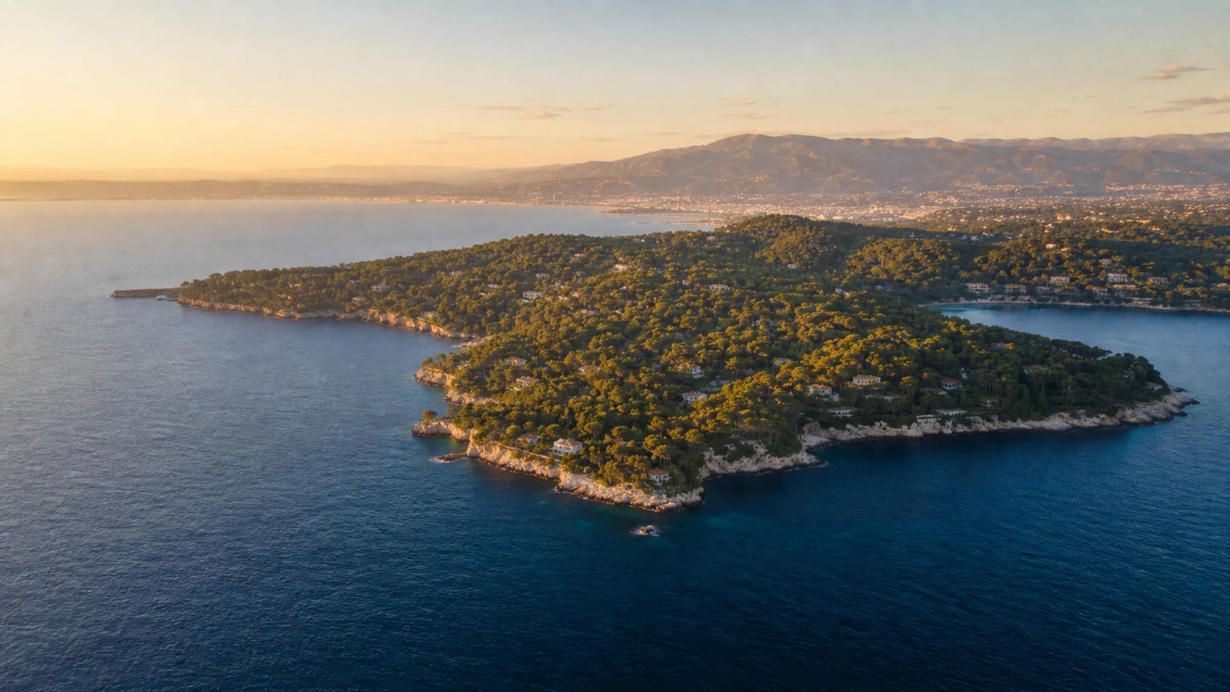 Aerial view of Cap d'Antibes peninsula villas above the Mediterranean at golden hour