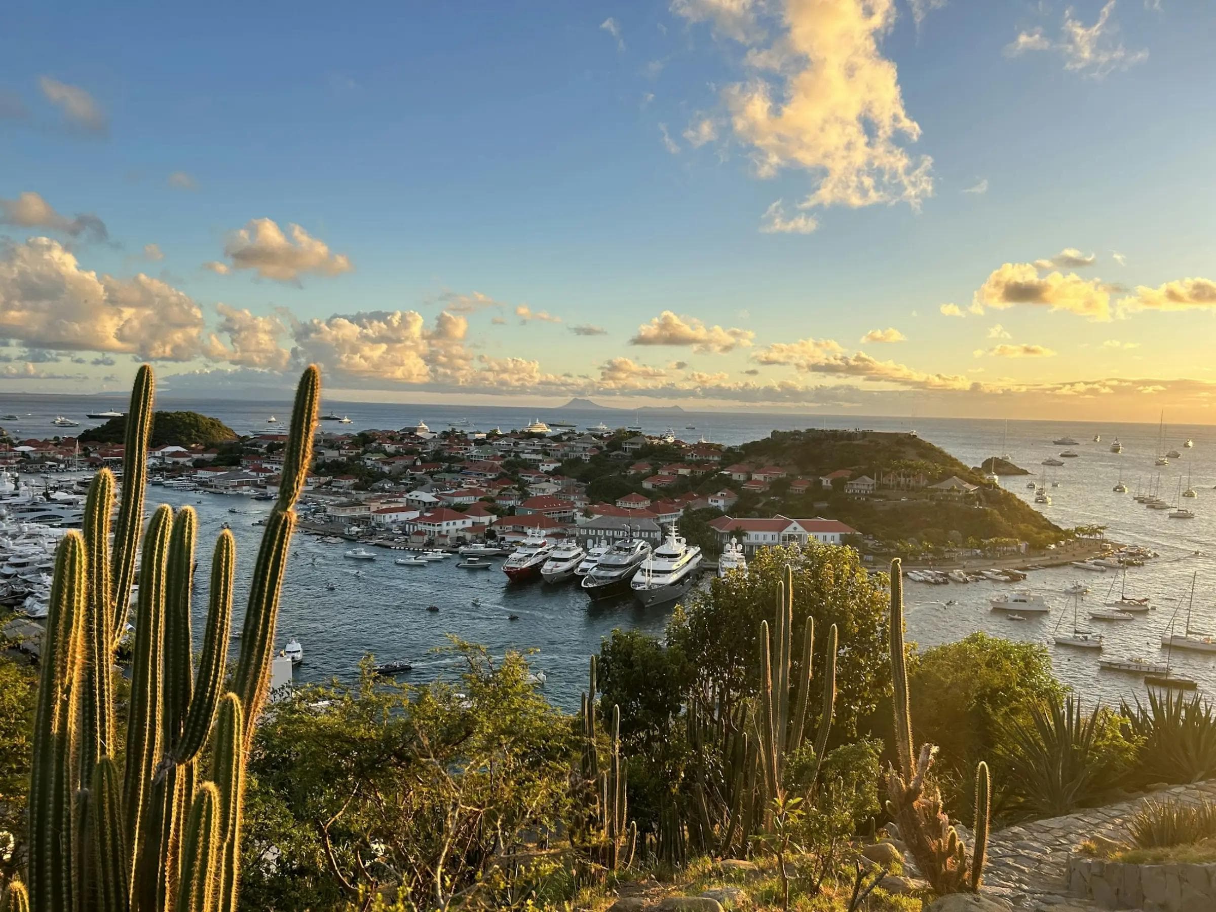 Superyachts anchored off Gustavia harbour in St Barths at golden hour during the winter charter season