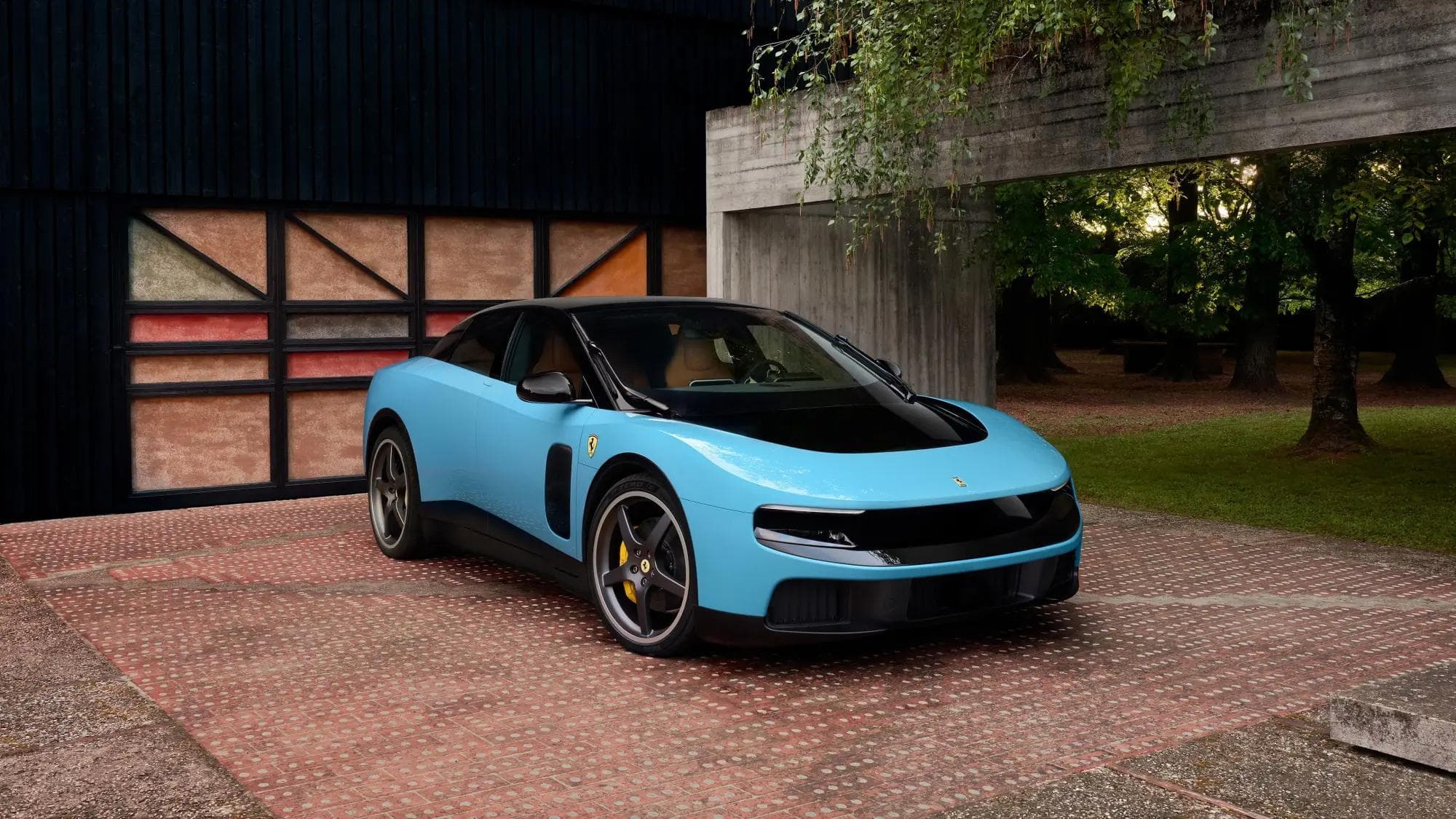Ferrari Luce in Tiffany Blue, front three-quarter exterior at a brick driveway with wood-panel garage and green trees in the background